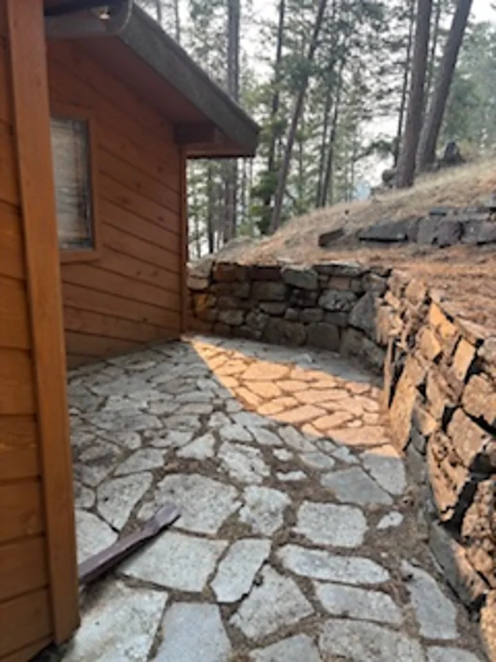 The same flagstone patio cleared down to bare stone, creating a noncombustible defensible space zone against the home