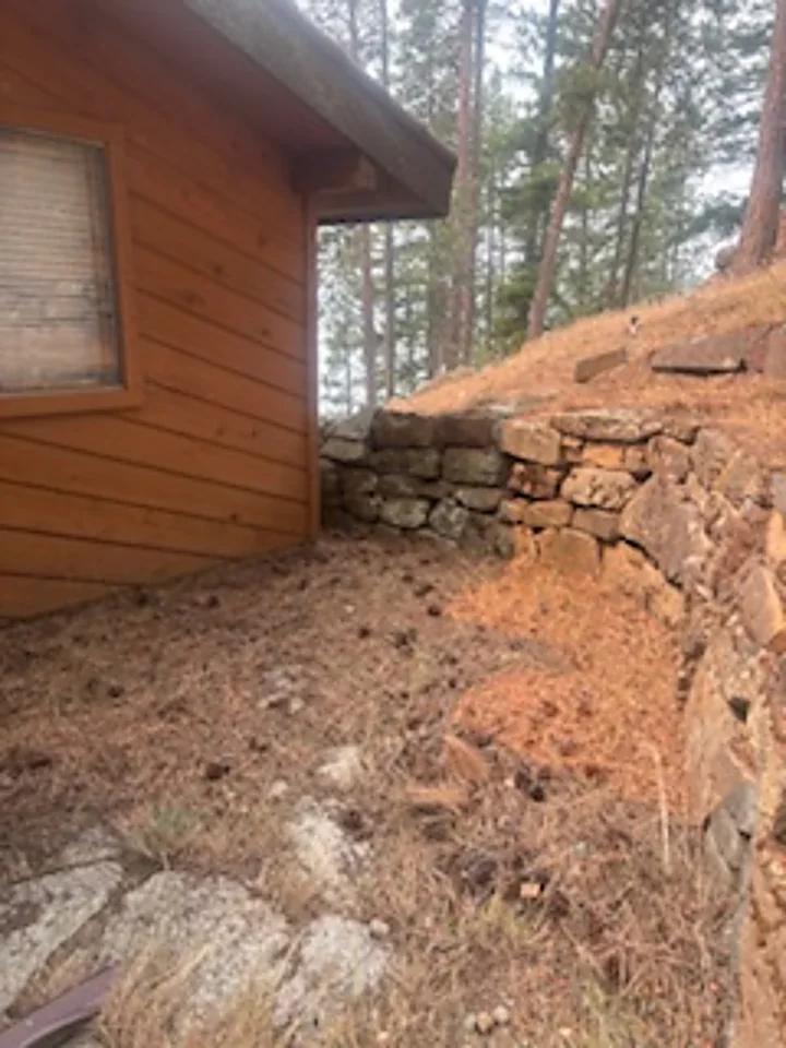 Flagstone patio buried under pine needles and duff against a log home near Sandpoint, Idaho before fire mitigation clearing
